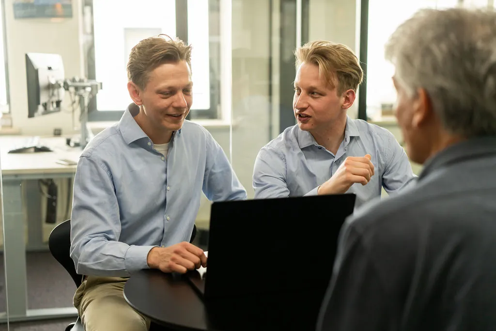 Twee ITsmart-collega's in overleg aan een ronde tafel met laptop