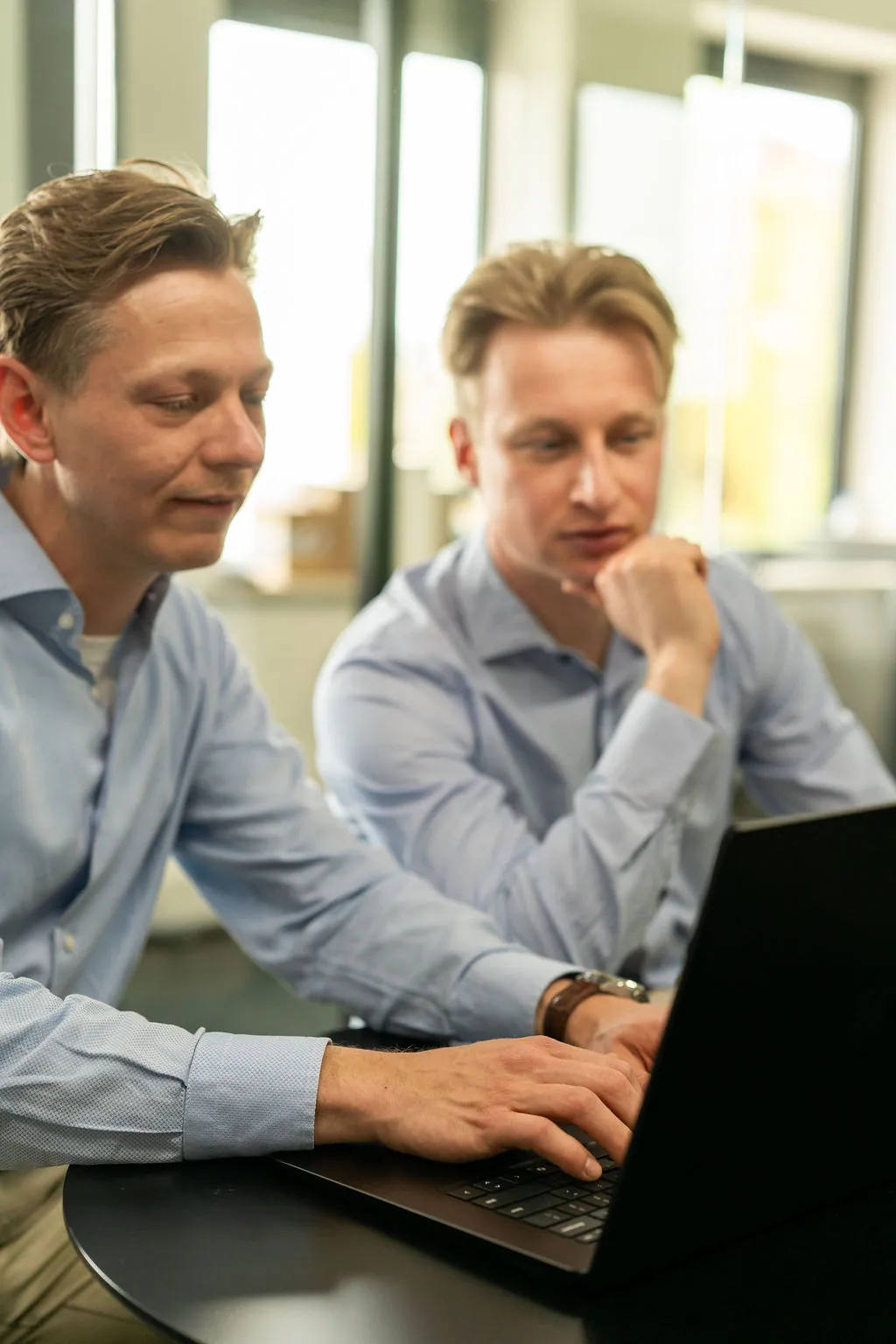 Twee collega's geconcentreerd aan het werk achter een laptop