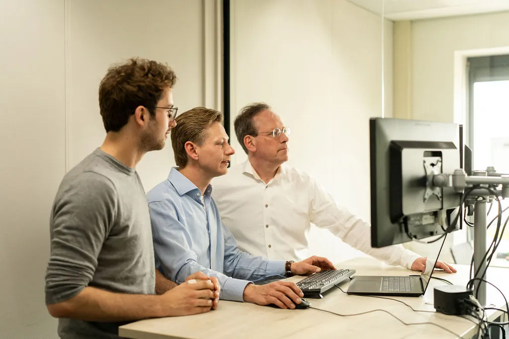 Drie ITsmart-collega's bekijken samen dashboard op monitor