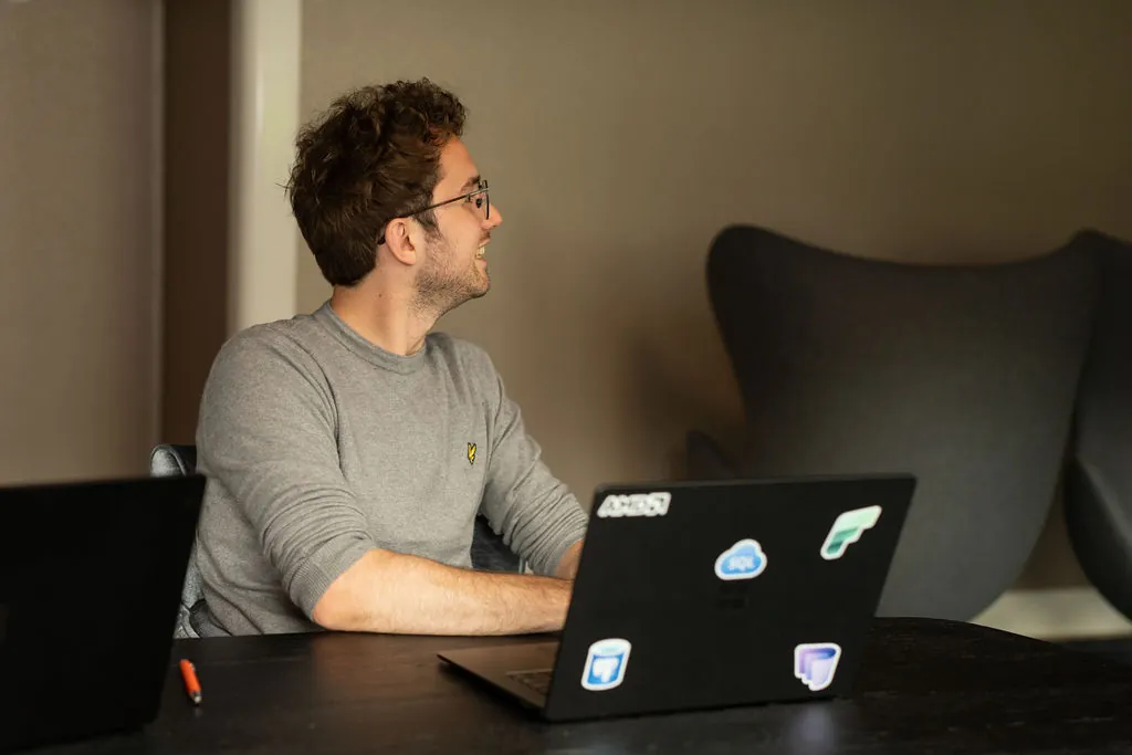 ITsmart-collega lachend achter een laptop met Azure-stickers